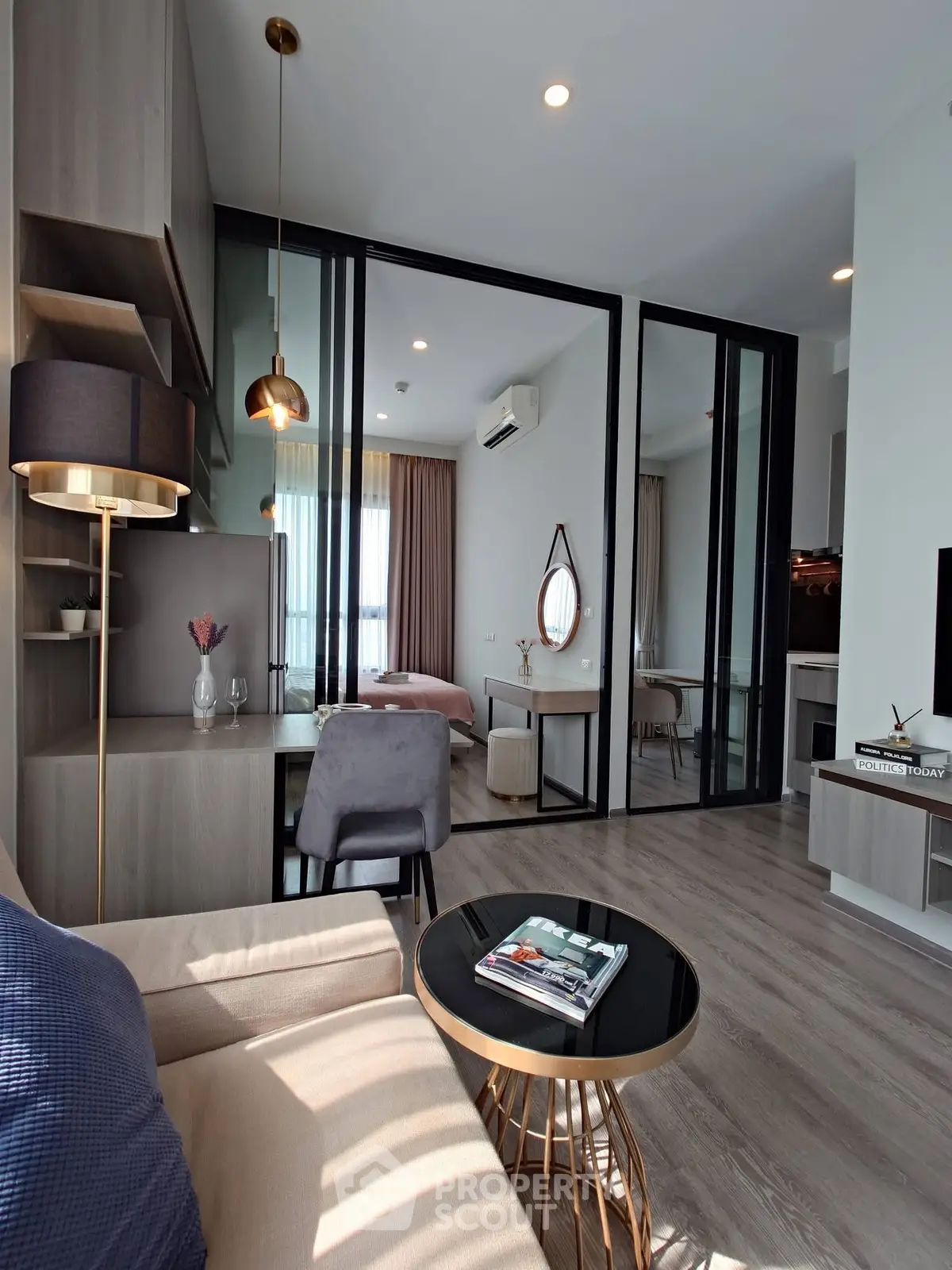 Modern living room with stylish decor and glass partition leading to bedroom