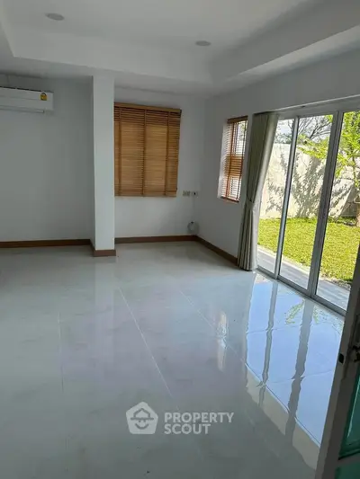 Spacious living room with large windows and garden view, perfect for natural light lovers.