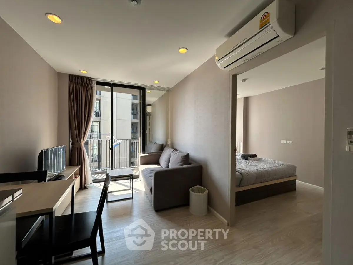 Modern apartment with open living room and bedroom, featuring sleek furniture and natural light.