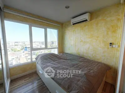 Cozy bedroom with large window offering stunning city views, featuring modern air conditioning and stylish decor.