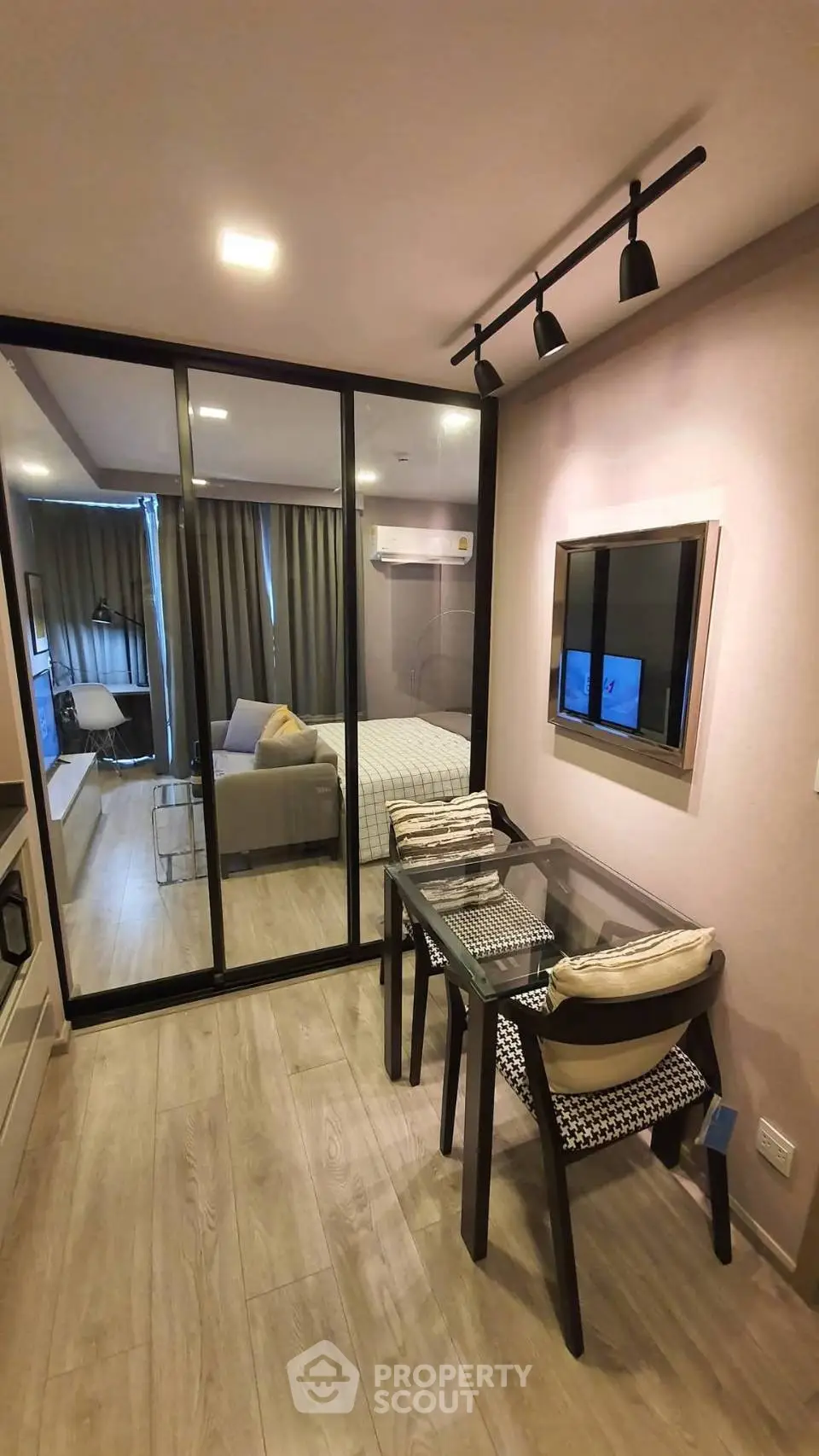 Modern apartment interior with glass partition, cozy dining area, and stylish decor.