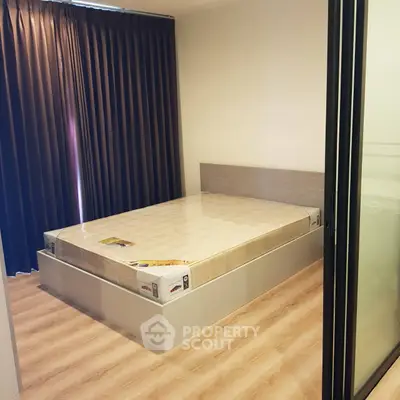 Modern bedroom with new mattress and wooden flooring, featuring floor-to-ceiling curtains for privacy.