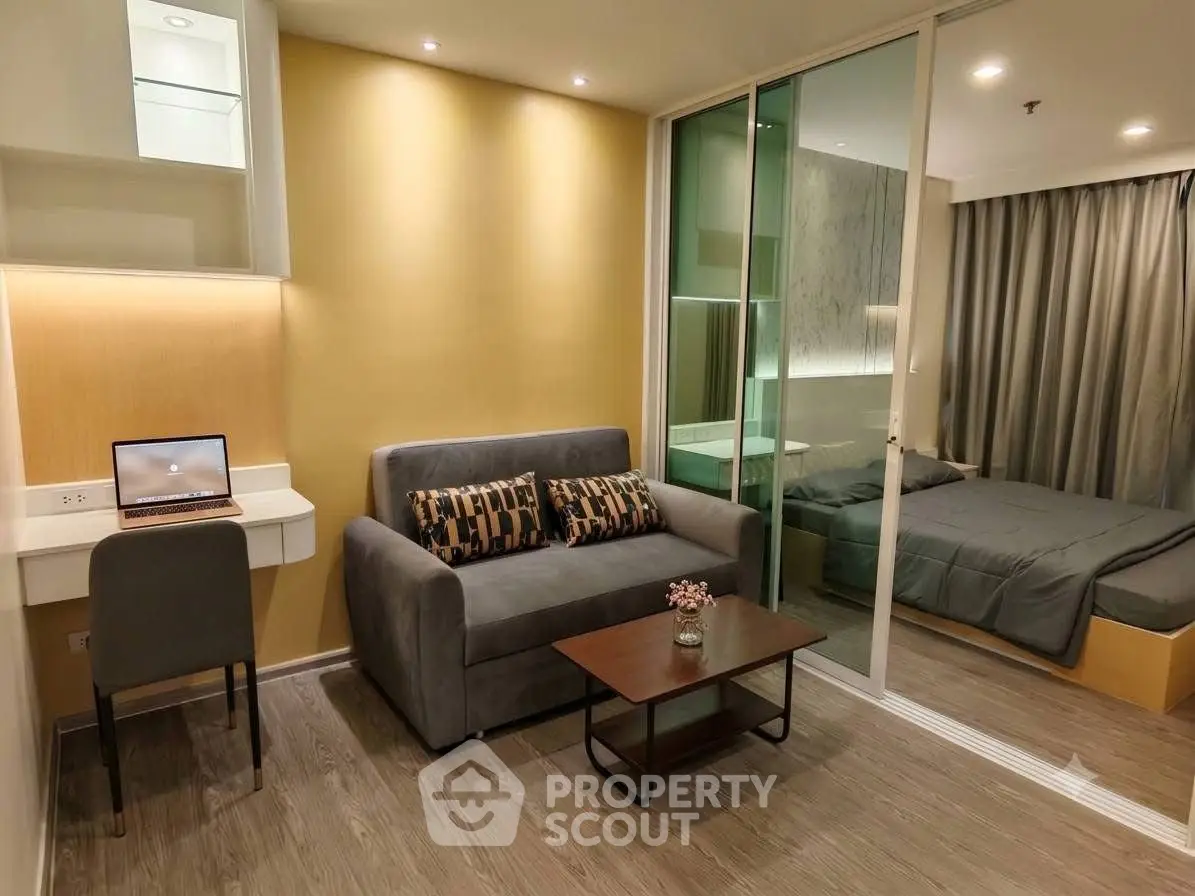 Modern studio apartment with cozy living area and bedroom separated by glass partition.