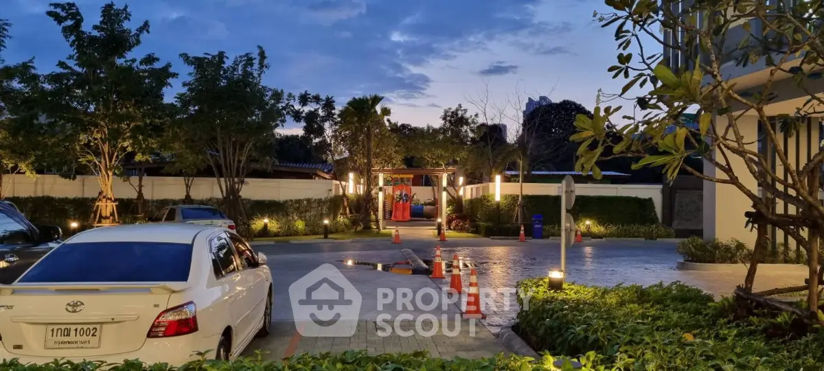Elegant residential entrance with lush greenery and ambient lighting at dusk.