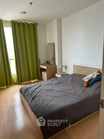 Cozy bedroom with modern furnishings and natural light through large window with green curtains.