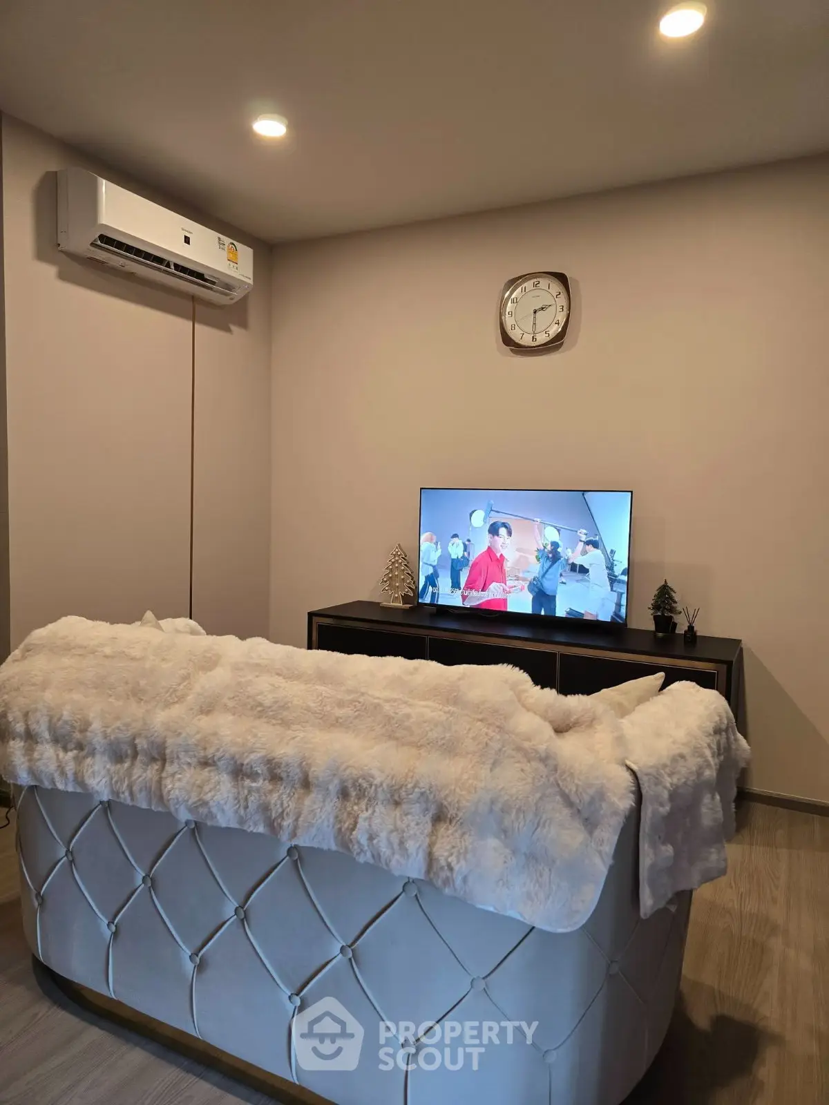 Cozy living room with plush sofa, wall-mounted TV, and air conditioning unit.