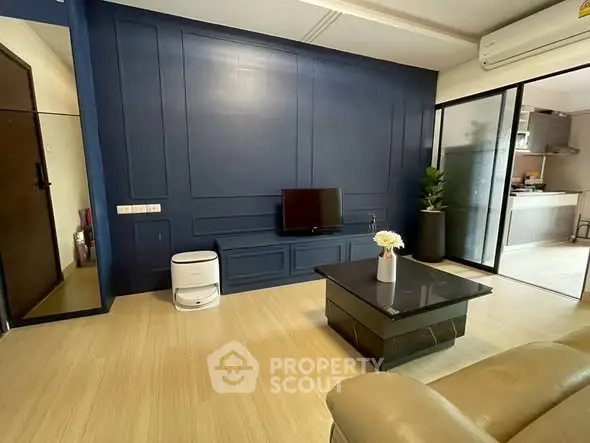 Modern living room with sleek blue accent wall and compact TV setup.