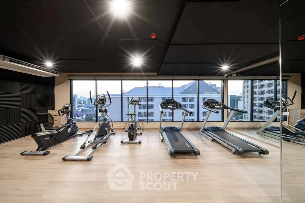 Modern gym with city view and state-of-the-art equipment in luxury apartment building.
