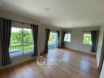 Spacious living room with large windows and balcony access, offering abundant natural light and serene views.