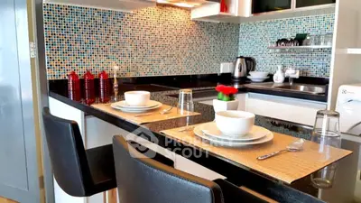 Modern kitchen with mosaic backsplash and sleek black countertops, featuring elegant dining setup.
