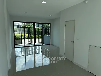 Spacious modern living room with glossy tiled floors and large windows overlooking garden.