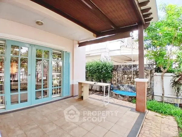 Charming patio with tiled flooring and lush garden view, perfect for outdoor relaxation.