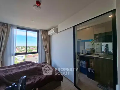 Modern bedroom with large window and view, adjacent to compact kitchen area.