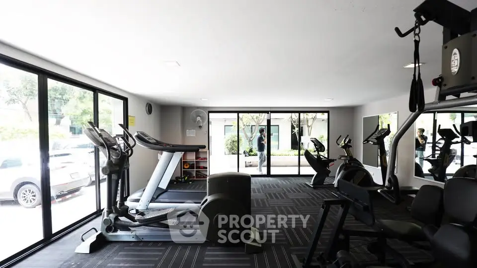 Modern gym with large windows and exercise equipment in a residential building.