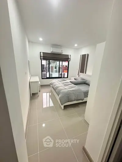 Modern bedroom with sleek design and large window for natural light.