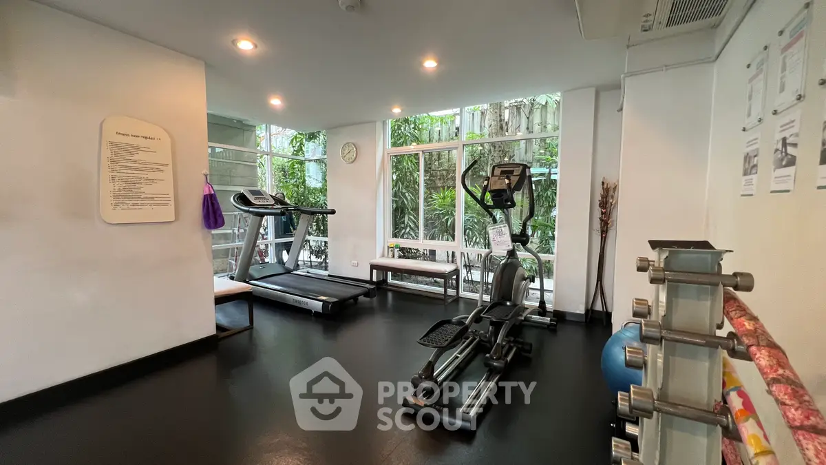 Modern gym with exercise equipment and large windows in a residential building.