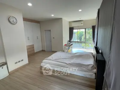 Spacious bedroom with large window and modern decor, featuring ample natural light and stylish furnishings.