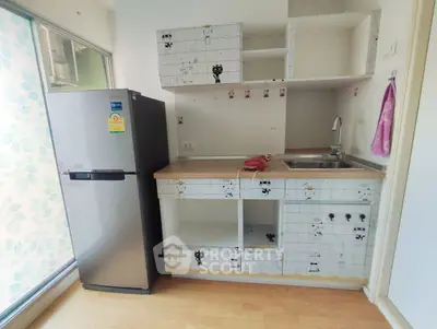 Compact kitchen with fridge and tiled backsplash in modern apartment