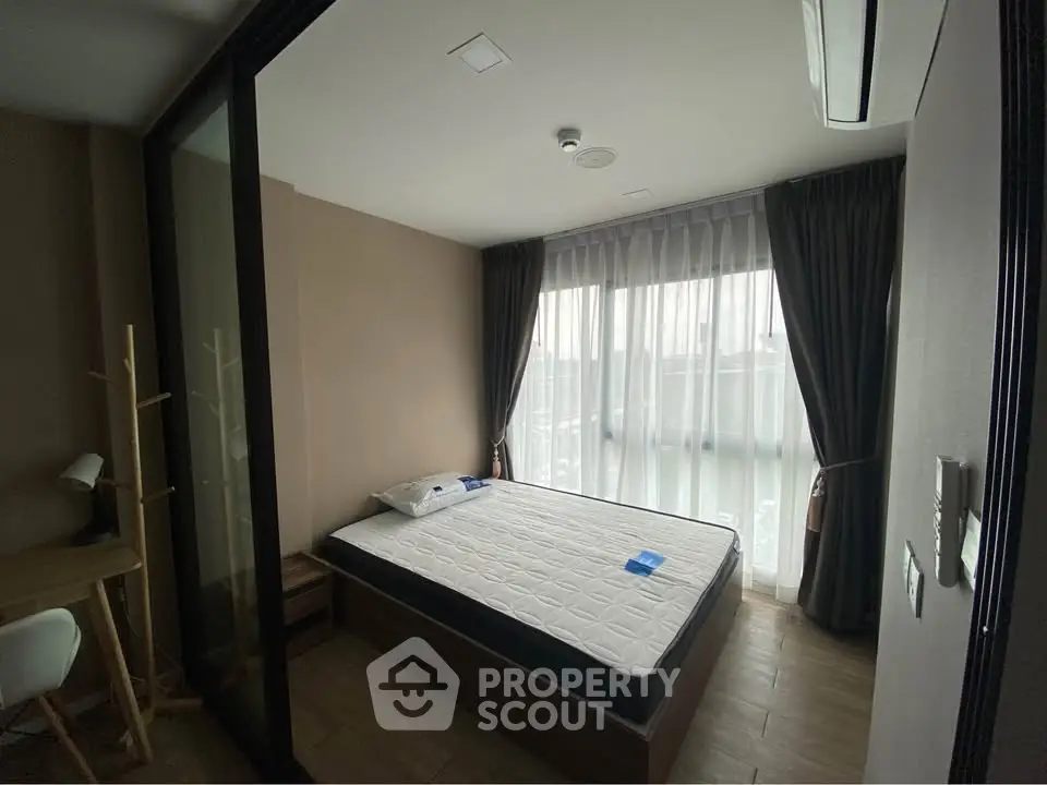 Cozy bedroom with large window and modern furnishings in a stylish apartment.