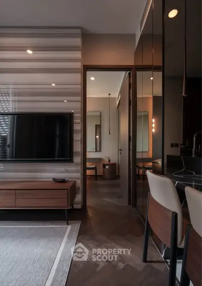 Modern living room with sleek design and stylish furniture, featuring a wall-mounted TV and elegant lighting.