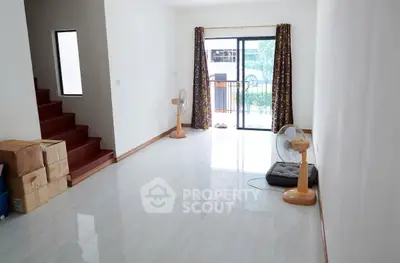 Spacious living room with large window and staircase, ideal for modern living.