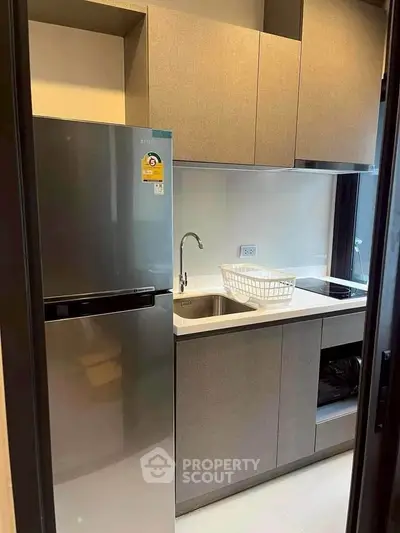 Modern compact kitchen with sleek cabinets and stainless steel appliances in a stylish apartment.