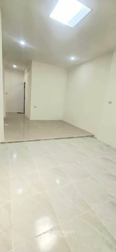 Spacious open-plan interior with tiled flooring and modern lighting, ideal for versatile living arrangements.