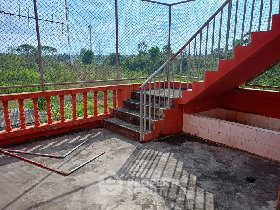 Spacious rooftop terrace with scenic views and red railing, perfect for outdoor relaxation.