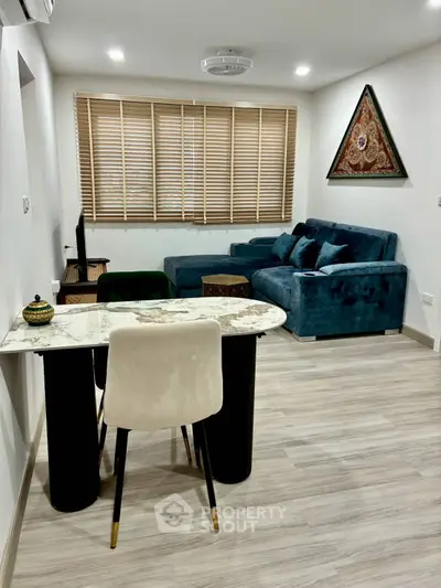 Modern living room with stylish decor and comfortable seating, featuring a marble table and large windows.