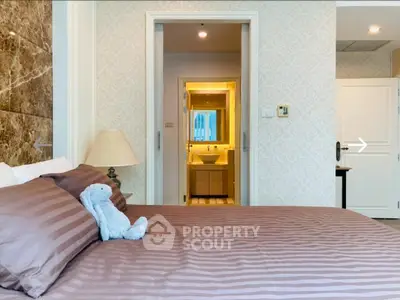 Luxurious bedroom with elegant decor and en-suite bathroom in modern apartment.