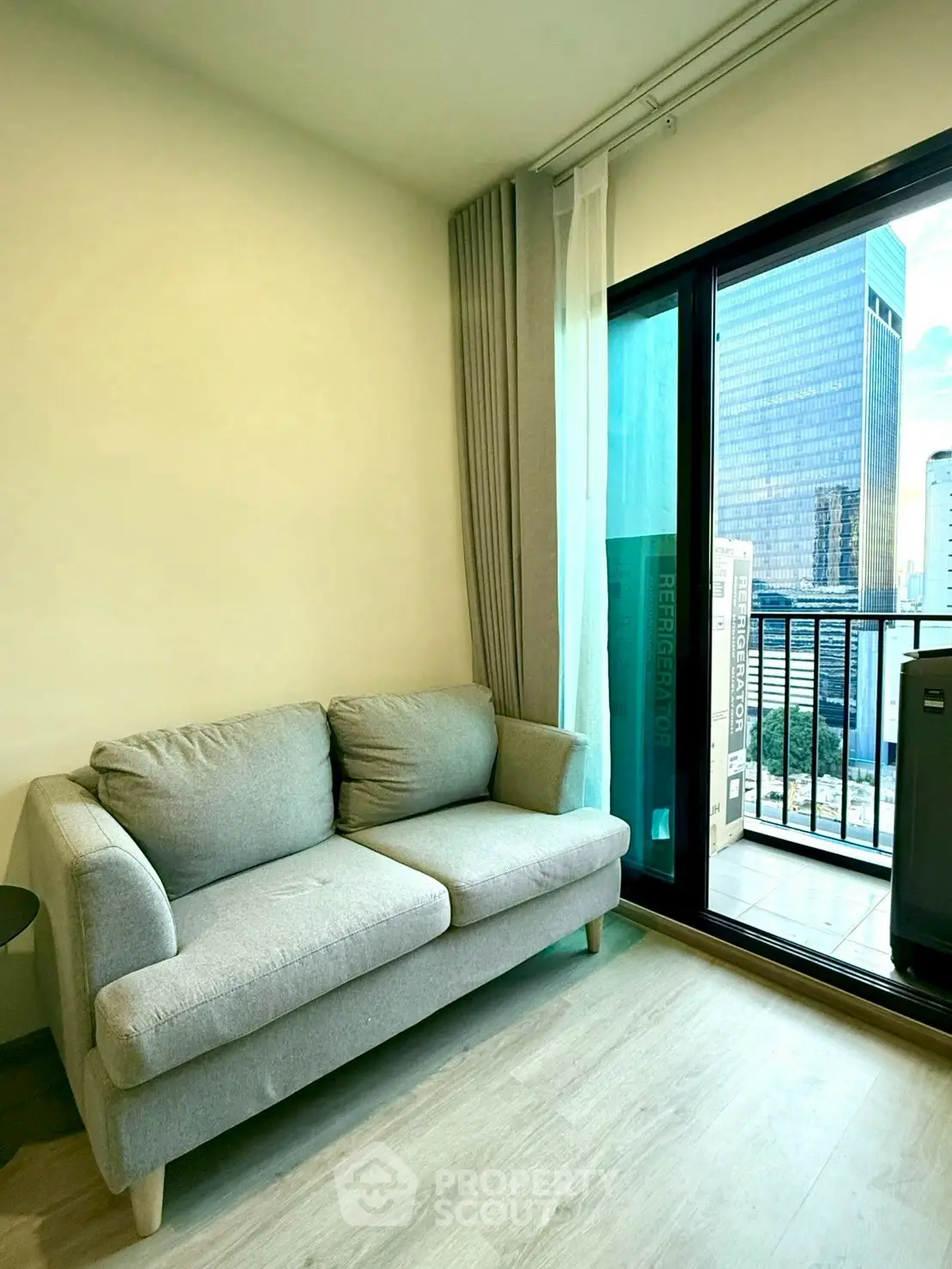 Modern living room with cozy sofa and city view balcony in high-rise apartment.