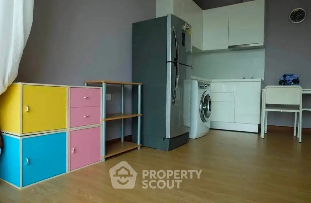 Modern kitchen with colorful storage, sleek appliances, and wooden flooring in a compact layout.