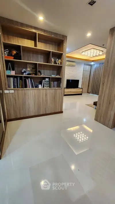 Spacious modern living room with built-in wooden shelves and elegant lighting