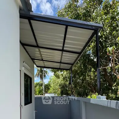Modern home exterior with sleek metal awning and lush greenery