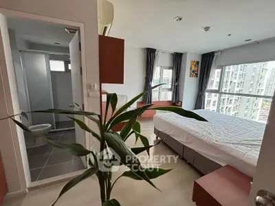 Modern bedroom with large windows and ensuite bathroom in a high-rise apartment.