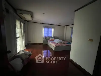 Cozy bedroom with wooden flooring and natural light, perfect for relaxation.