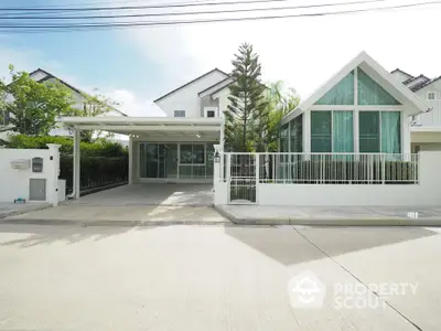 Modern white house with large windows and spacious driveway in a serene neighborhood.