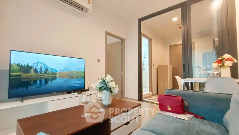 Modern living room with stylish decor and open layout, featuring a cozy sofa and flat-screen TV.