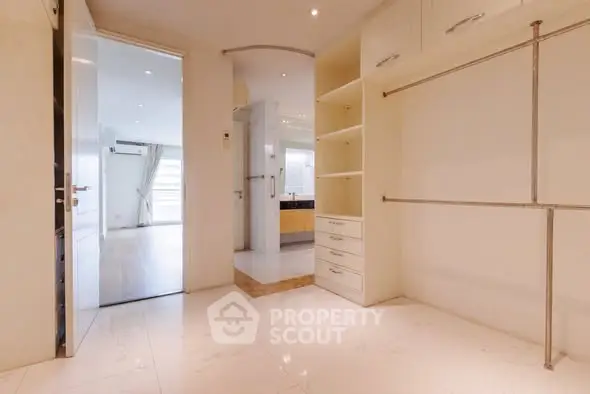 Spacious walk-in closet with ample shelving and hanging space in modern apartment.