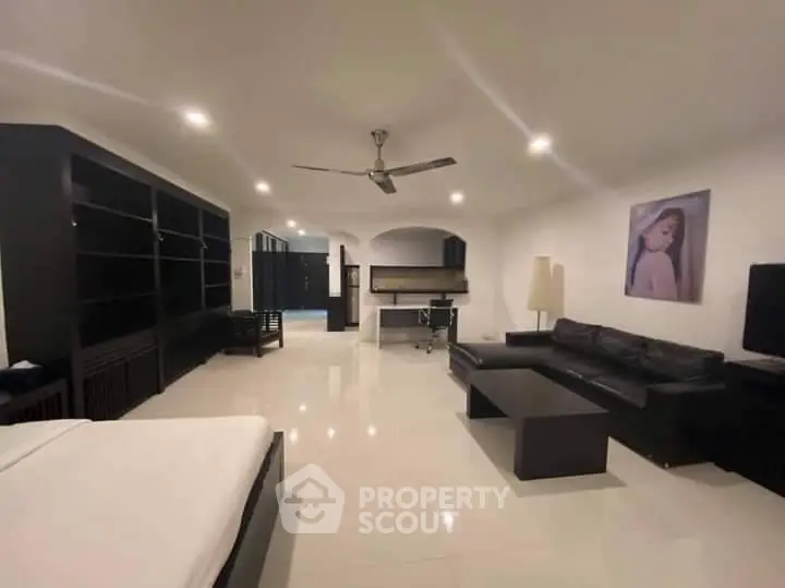Spacious modern living room with glossy white tiles, elegant black furniture, and a sophisticated ceiling fan, perfect for upscale urban living.
