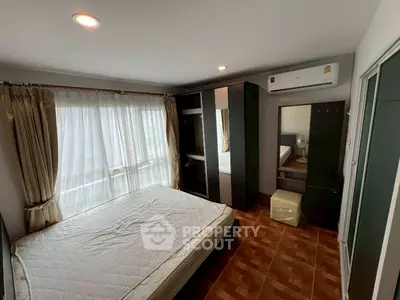 Spacious bedroom with large window and modern furnishings