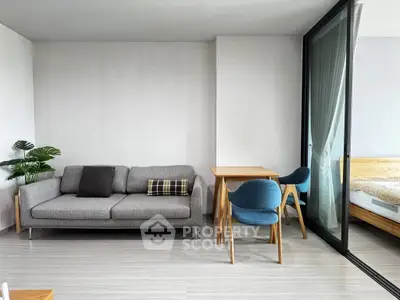 Modern living room with sleek furniture and large glass doors leading to a bedroom.
