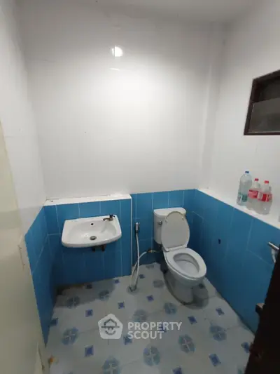Compact bathroom with blue and white tiles, featuring a toilet and wall-mounted sink.