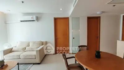 Modern living room with cozy sofa and dining area, featuring wooden doors and air conditioning.