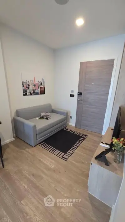 Modern living room with sleek wooden flooring and cozy gray sofa, perfect for urban living.