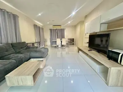 Spacious modern living room with sleek furniture and large TV, perfect for relaxation and entertainment.