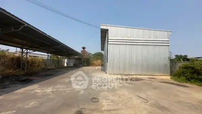 Industrial warehouse exterior with spacious outdoor area and metal structure, ideal for storage or manufacturing.