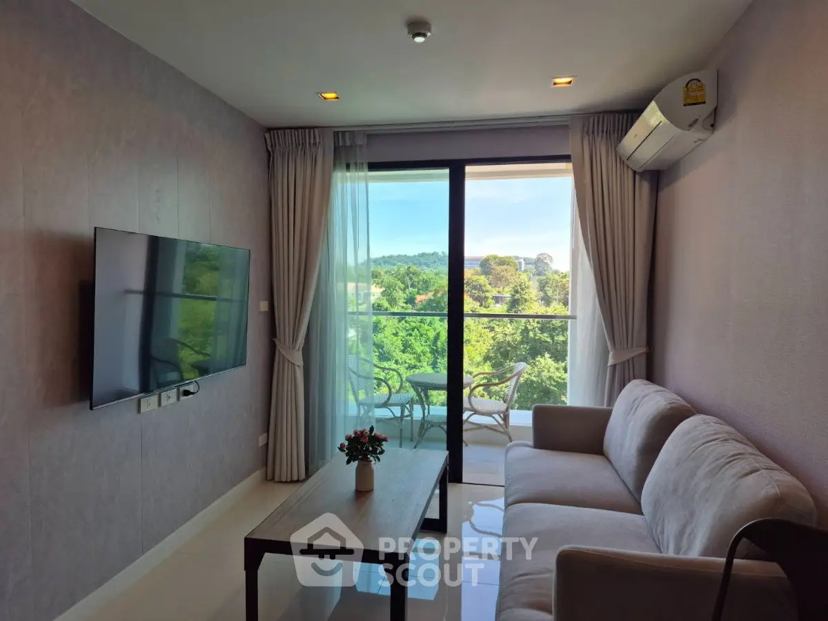 Modern living room with balcony and scenic view, featuring cozy sofa and wall-mounted TV.