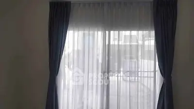 Elegant room with large window and sheer curtains offering natural light and outdoor view.