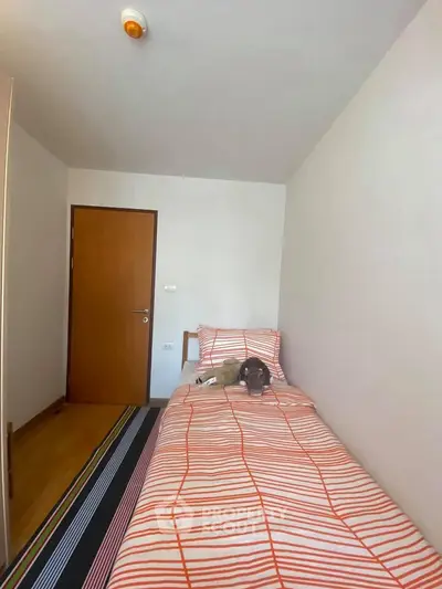 Cozy bedroom with single bed and striped bedding, perfect for a minimalist lifestyle.